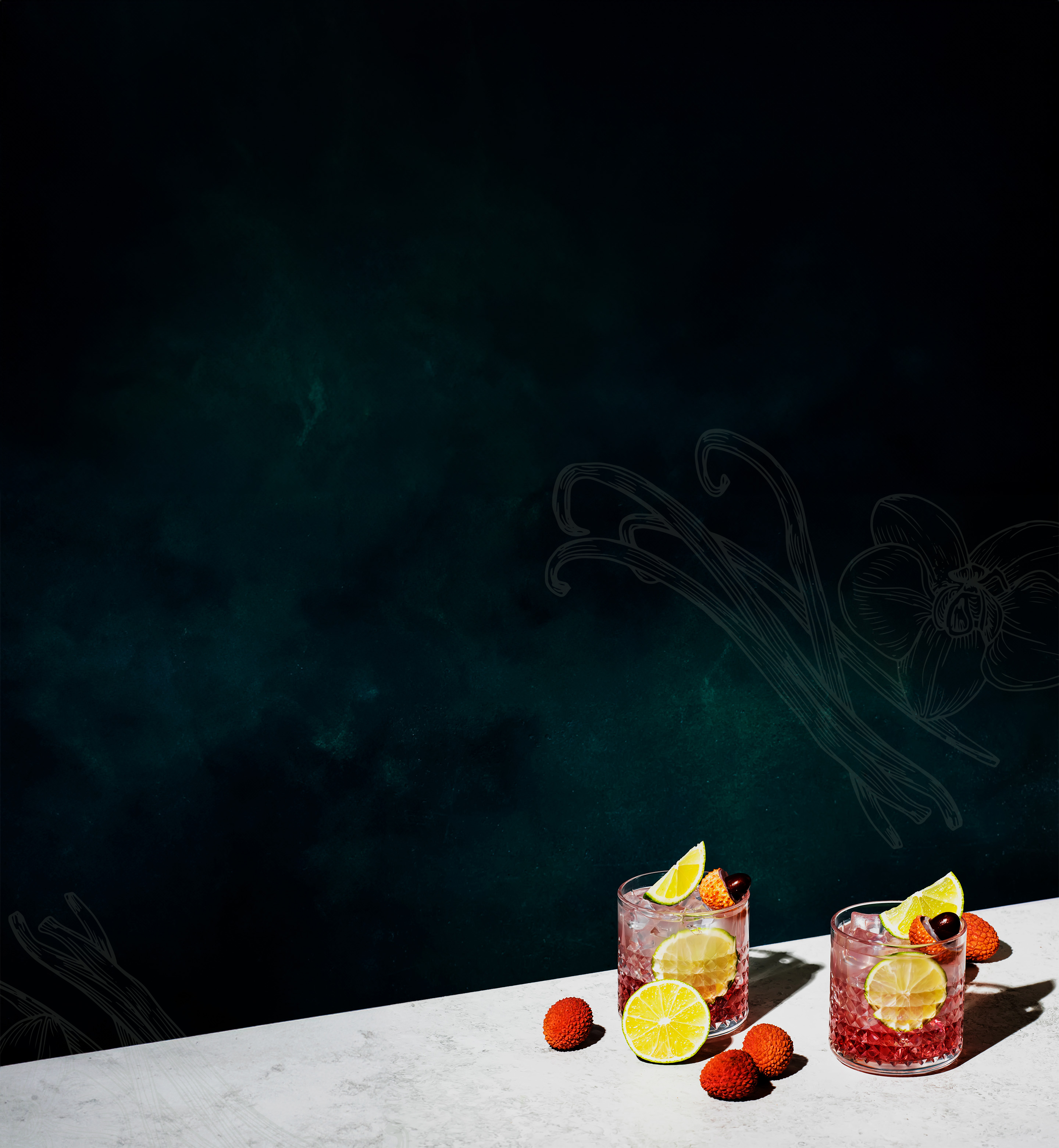 Two cocktail drinks with ice and fruit sitting on a white marble countertop against a dark green background